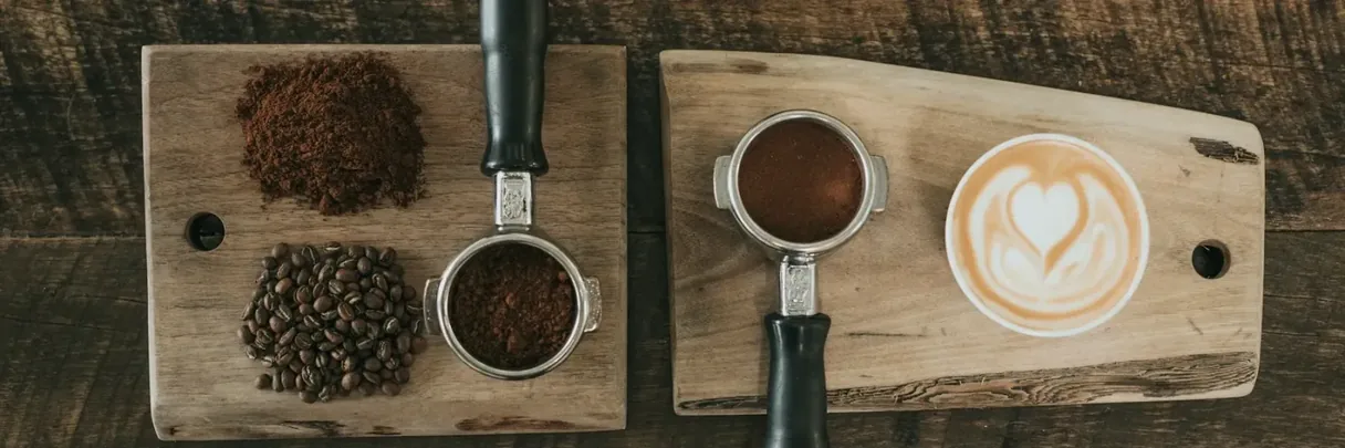 Ground coffee, beans, espresso and a latte on a serving board